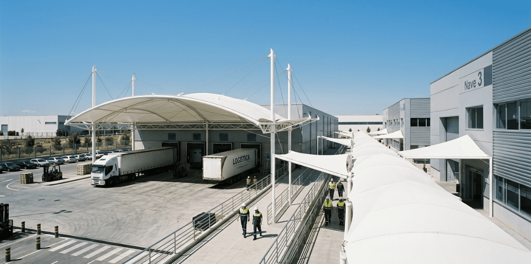 Andenes de carga en empresa de logística industrial protegidos con membranas arquitectónicas de alta resistencia y protección UV para operaciones exteriores.